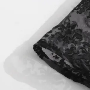 Dettaglio ravvicinato del tessuto in pizzo floreale nero con motivi jacquard fini.