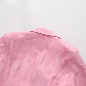 Détail du tissu texturé rose et du col d'une veste de blazer de style minimaliste.