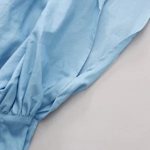Detail van een lichtblauw hemd met pofmouwen met delicate stiksels en plooien