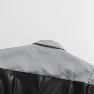 Detailopname van grijze stof en zwart leer op een minimalistisch blazerjack voor dames.