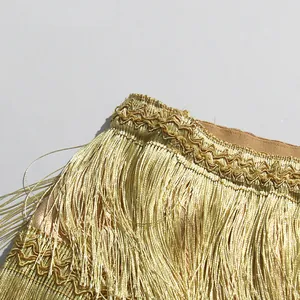 Detailed view of champagne gold layered fringe skirt with intricate wavy stitching