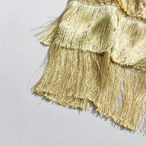 Detailed close-up showing the layered gold fringe texture of a fashionable midi skirt.