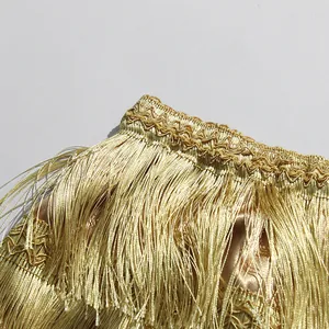 Close-up detail of a gold metallic layered fringe skirt featuring elegant embroidery