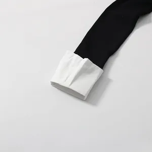 Close-up of black knit sleeve with white shirt cuff detail on fake two-piece top.