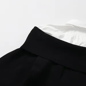Close-up detail of the black ribbed knit and white shirt collar patchwork on a women's top