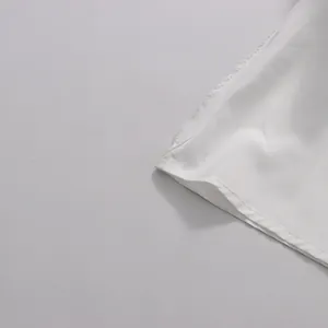 Gros plan sur les coutures fines et la texture du tissu blanc de l'ourlet d'une jupe.