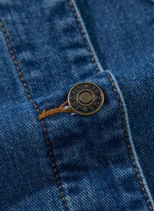 Makroaufnahme eines Vintage-Metallknopfes auf einem hochwertigen blauen Jeansstoff