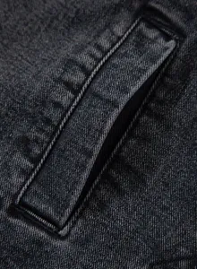 Makro-Detail des hochwertigen grauen Denim-Stoffs und der Tasche an der Damenjacke