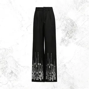 Detailed view of black high-waist straight pants with silver sequined geometric patterns.
