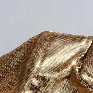 Macro view of the shimmering golden sequin fabric detail on a luxury fashion blazer