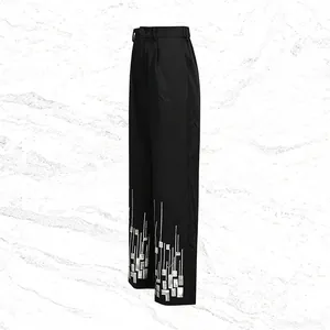 Close-up of black high-waist straight trousers with silver sequin geometric patterns
