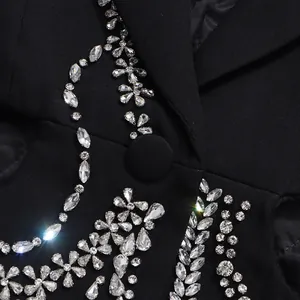 Macro detail of intricate floral rhinestone patterns on a high-end black suit jacket.