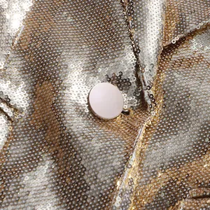 Close-up detail of high-quality gold sequin fabric with a champagne round button