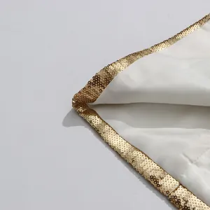 Close-up of elegant white garment edge featuring intricate gold sequin trim detail