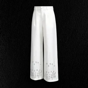 Detail of white high-waist straight-leg trousers with silver geometric sequin patterns.