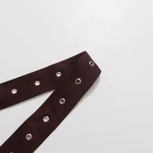 Close-up of burgundy suede belt with double row silver metal grommets for windbreaker.