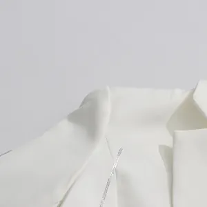 Detailed view of the elegant white blazer featuring shiny silver sequin trim on the lapels.