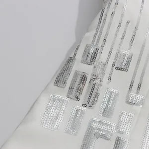 Exquisite close-up of shiny silver sequin patterns on premium white garment fabric detail