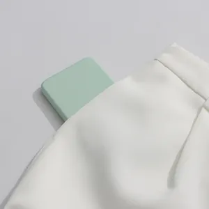 Detail view of the deep side pocket on white high-waisted trousers from a fashion set.