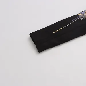Détail de la broderie complexe en paillettes de feu d'artifice sur la manche d'un blazer noir