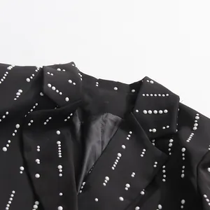 Close-up of a black blazer featuring elegant white pearl bead decorations on the lapel