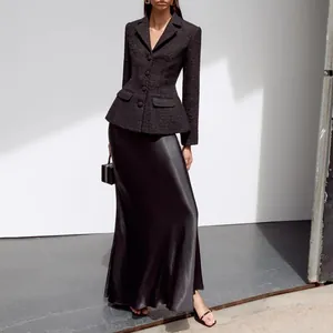 Close-up of elegant black tweed jacket paired with a sleek satin high-waisted long skirt.