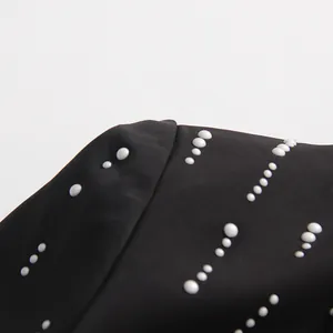 Close-up detail showing exquisite white pearl decorations on a black high-end women's blazer jacket