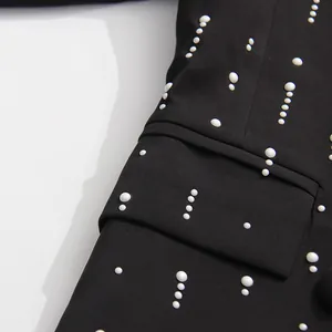 Close-up detail of white pearl decorations on a stylish black tailored blazer jacket