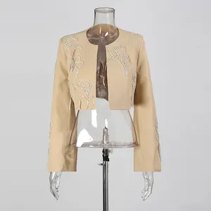 Dettaglio di un'elegante giacca corta beige con intricati motivi in strass