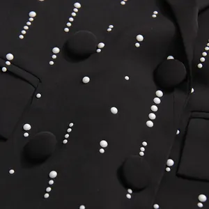 Detail of black blazer featuring elegant white pearl beads and large fabric buttons