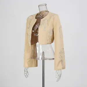 Elegante giacca corta beige con intricato ricamo floreale di strass su un manichino.