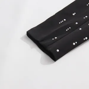 Detail shot of elegant white pearl embellishments on a black blazer sleeve cuff