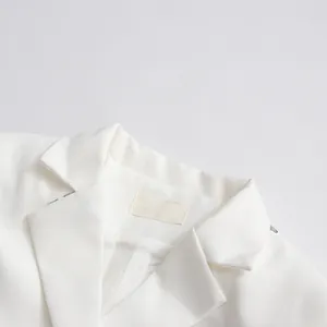 Close-up view of a white sequined lapel blazer top detailing collar and fabric texture