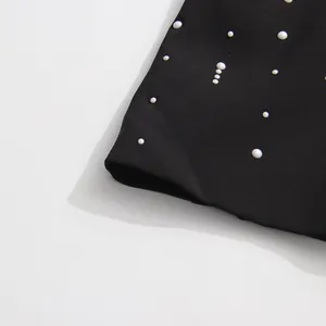 Detailed close-up showing elegant white pearl decorations on high-quality black suit fabric