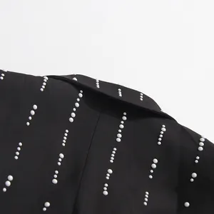 Close-up detail of white pearl embellishments on a premium black tailored blazer jacket
