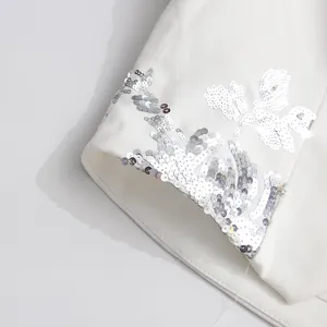 Close-up detail showing the silver sequin floral embroidery on a white fashion top lapel.
