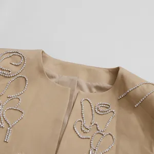 Dettaglio di giacca beige da donna con ricamo di strass pesanti in design a vortice