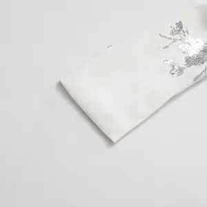 Detailed macro view of elegant silver sequin floral embroidery on a white fashion top