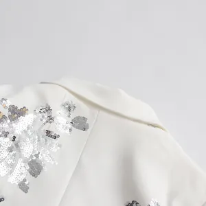 Close-up detail of white sequined blazer showing collar and silver floral embroidery