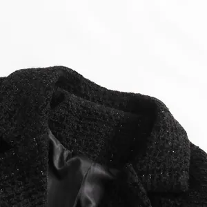 Close-up of black tweed jacket collar featuring shimmering metallic fiber texture.