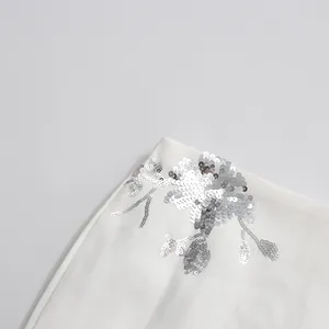 Detailed close-up showing silver floral sequin embroidery on premium white fabric