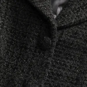 Detailed macro shot of elegant black shimmer tweed fabric and matching button on jacket