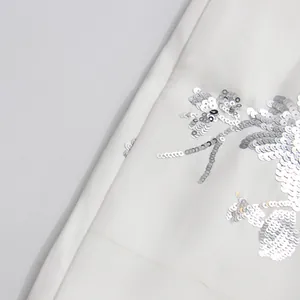 Detailed macro view of silver sequin embroidery on premium white fashion fabric