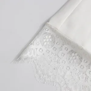 Close-up detail of delicate white floral lace hem with eyelash trim on elegant skirt