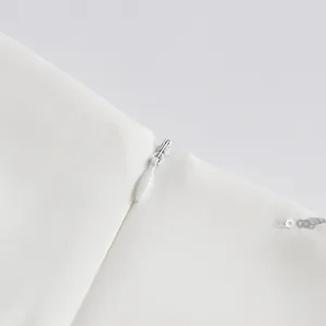 Close-up of white fabric with invisible zipper and silver sequin details for skirt