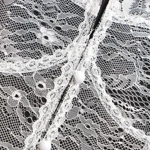 Gros plan sur la texture complexe de la dentelle blanche et les boutons sur fond noir