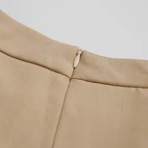 Dettaglio della cerniera a scomparsa sui pantaloni eleganti beige a vita alta e gamba larga