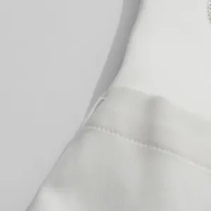 Macro view of high-quality white fabric and stitching detail on a minimalist women blazer