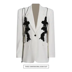 Detail of white blazer featuring intricate black sequin 3D bow embellishments.