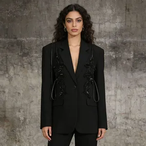 Model wearing a black blazer with sequin butterfly applique and decorative straps.